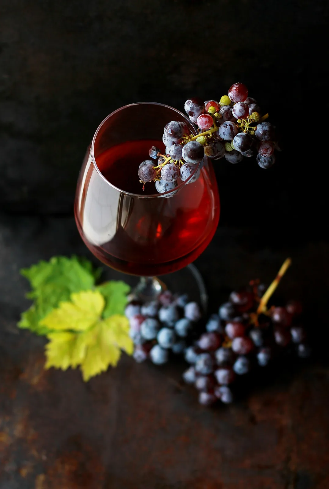 A glass of red wine beside fresh grapes